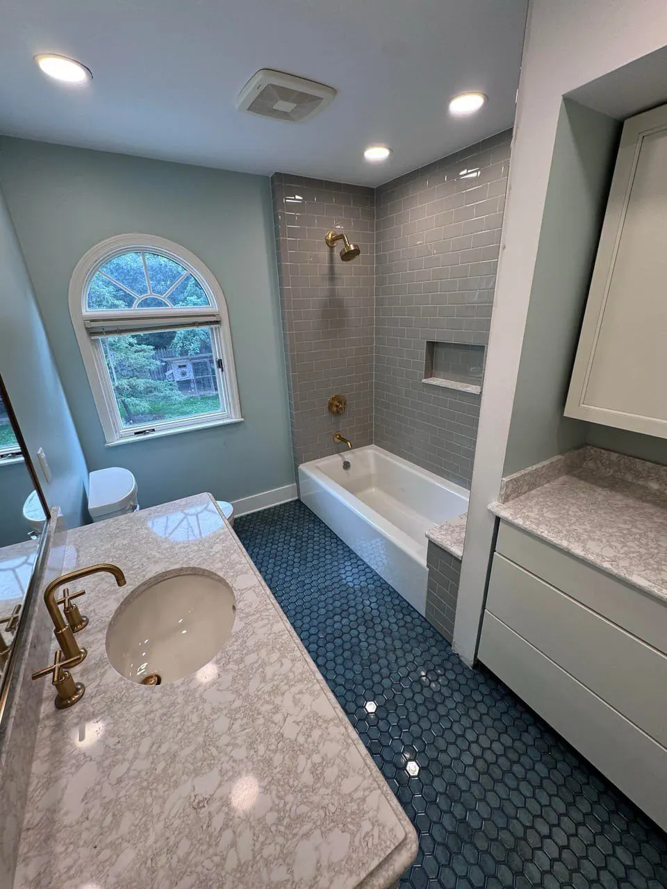 Bathroom remodel with marble-look tile tub surround and arched window — Fenelon Handyman Services, Tampa Bay, FL