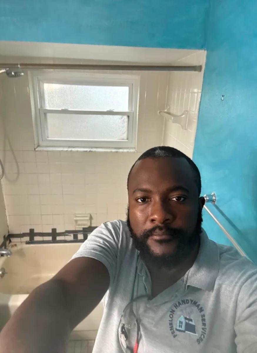 Fenelon owner in front of the old cream 4x4 tile tub surround before demolition during a Tampa small bathroom rehab